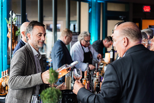 Man pouring wine into guests glass.